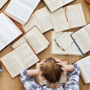 girl looks over several books to find the best act test prep book