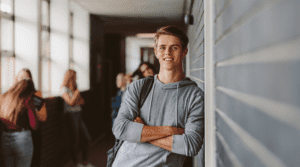 high school boy leans against locker in hallway after leaving college prep course in high school
