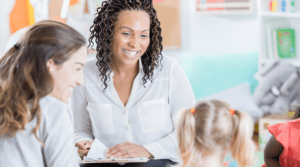 A female tutor smiles at a daughter with her mom as they discussing what they're considering when choosing a tutor.